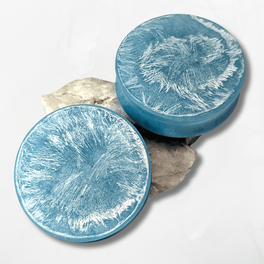 Two light blue double flared, stretched ear plugs with a white textured surface on a white background